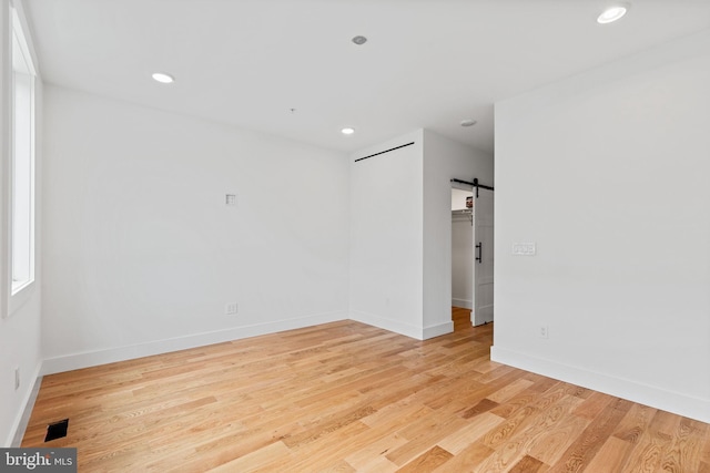 spare room featuring light hardwood / wood-style floors and a barn door