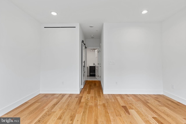 empty room with a barn door and light wood-type flooring