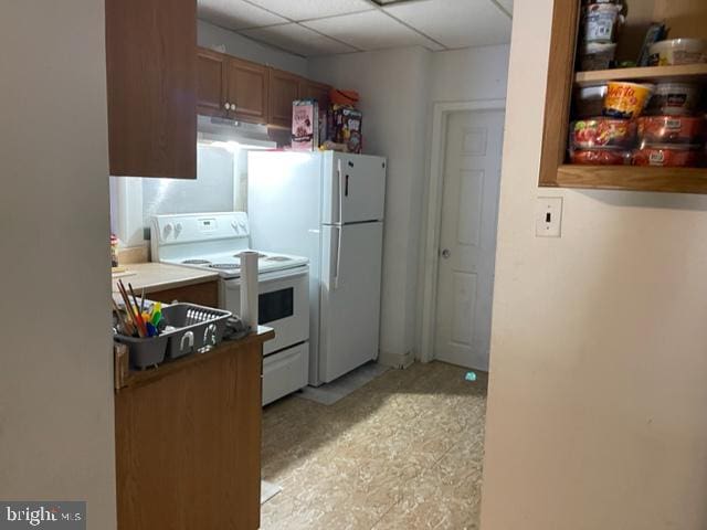 kitchen with white appliances, a paneled ceiling, and light tile floors