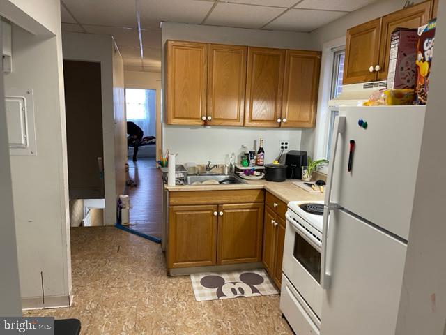 kitchen featuring light tile floors, white appliances, a drop ceiling, and sink