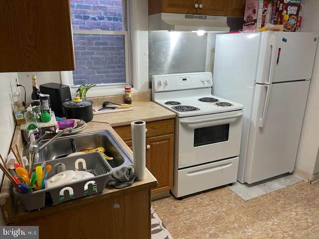 kitchen with white appliances, sink, custom range hood, and light tile floors