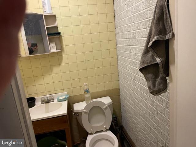 bathroom with tile walls, toilet, and vanity with extensive cabinet space