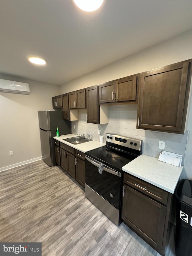 kitchen with dark brown cabinets, tasteful backsplash, light wood-type flooring, sink, and appliances with stainless steel finishes