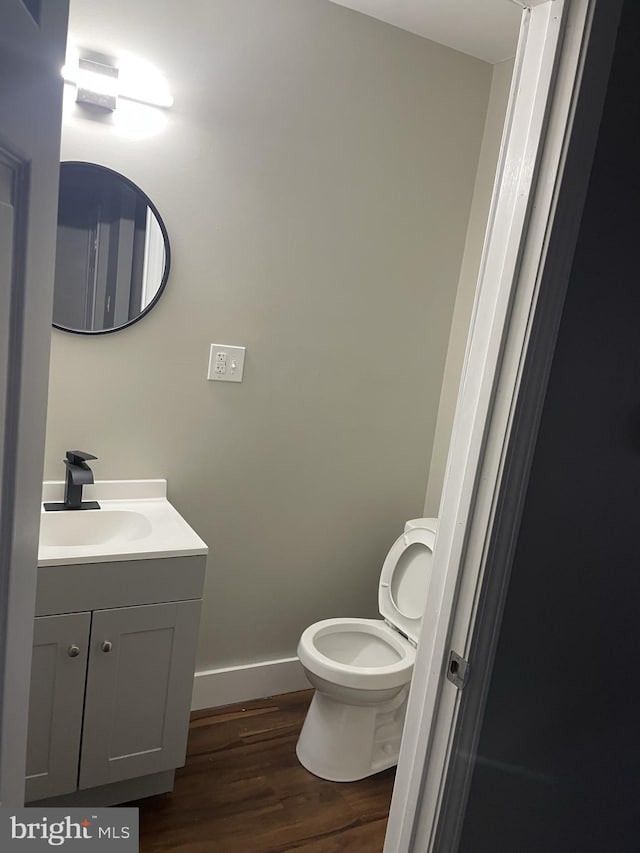 bathroom with vanity, toilet, and hardwood / wood-style flooring