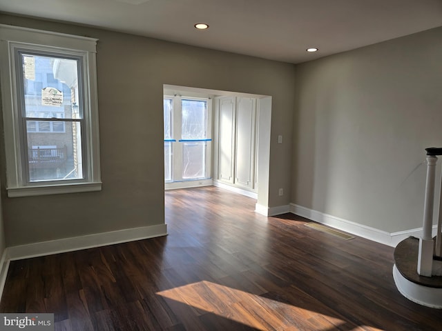 unfurnished room featuring plenty of natural light and dark wood-type flooring