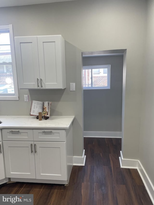 kitchen with dark hardwood / wood-style floors, white cabinets, and light stone countertops