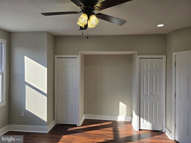 interior space with dark hardwood / wood-style floors, ceiling fan, and two closets