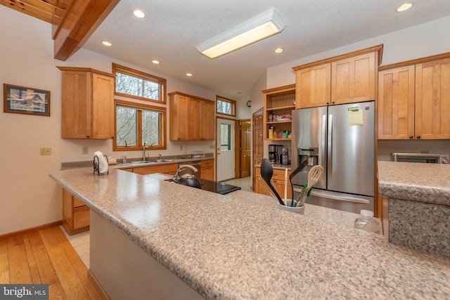 kitchen featuring kitchen peninsula, sink, lofted ceiling with beams, appliances with stainless steel finishes, and light hardwood / wood-style floors