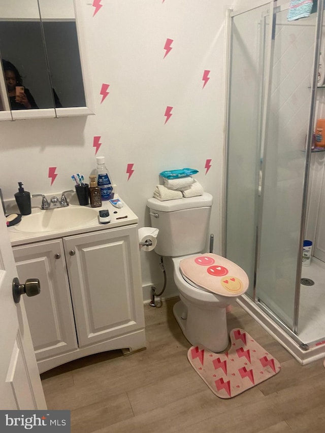 bathroom featuring hardwood / wood-style flooring, an enclosed shower, toilet, and vanity