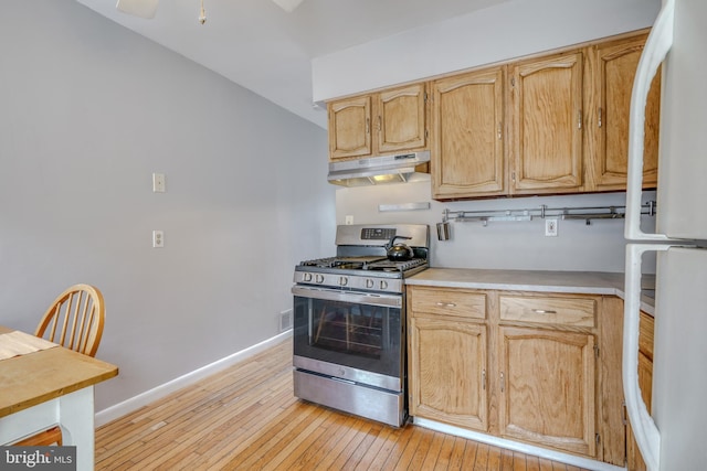 kitchen with white refrigerator, light hardwood / wood-style flooring, ceiling fan, and stainless steel gas range oven