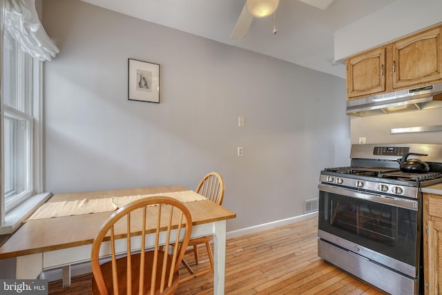 kitchen featuring light hardwood / wood-style flooring, ceiling fan, and stainless steel gas range oven