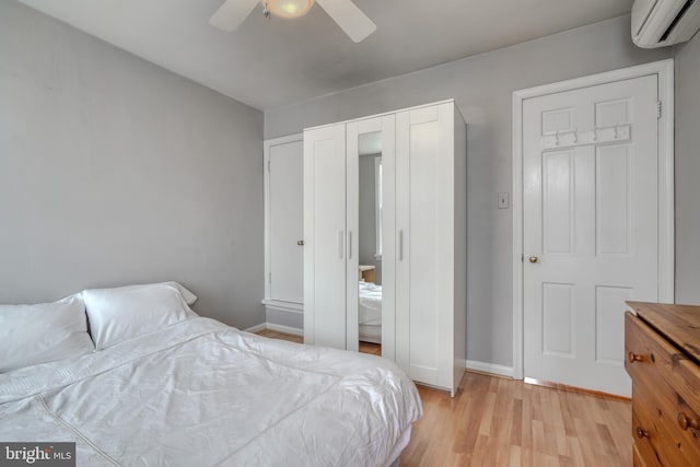 bedroom with light hardwood / wood-style floors, ceiling fan, and a wall mounted air conditioner