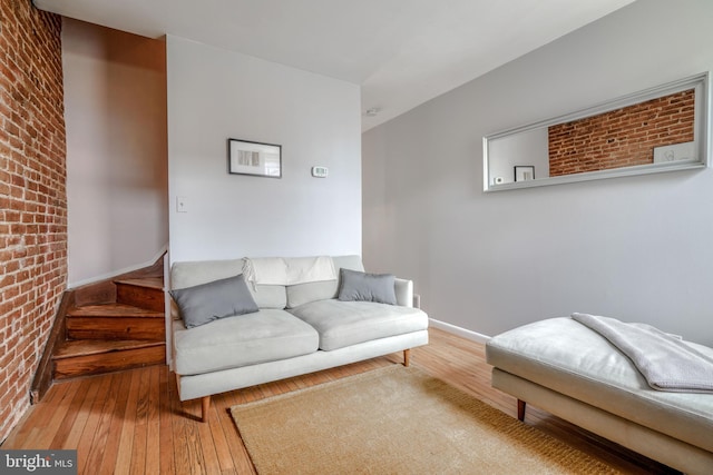 living room featuring brick wall and hardwood / wood-style flooring