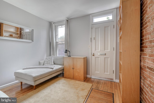 sitting room with light hardwood / wood-style flooring and brick wall