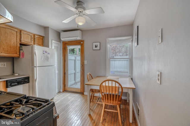 kitchen featuring a wall unit AC, light hardwood / wood-style flooring, ceiling fan, and white appliances