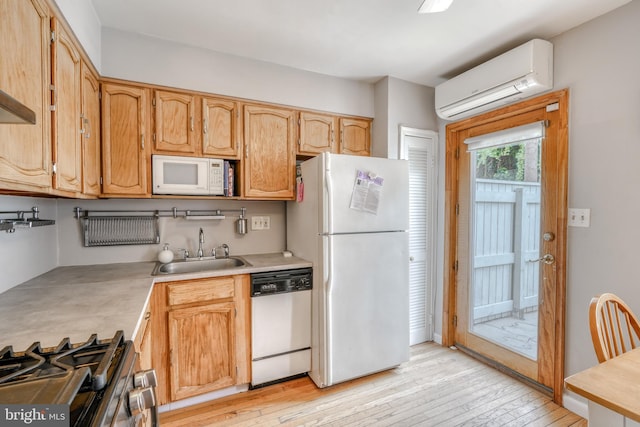 kitchen featuring sink, white appliances, a wall mounted AC, and light wood-type flooring