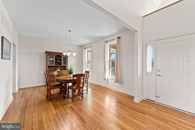 dining area with an inviting chandelier, a wealth of natural light, and light hardwood / wood-style floors