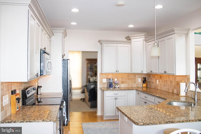 kitchen featuring stone counters, appliances with stainless steel finishes, sink, light hardwood / wood-style flooring, and pendant lighting