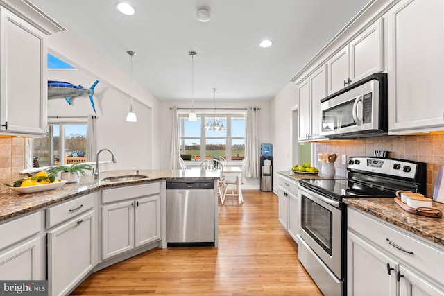 kitchen featuring pendant lighting, light wood-type flooring, stainless steel appliances, backsplash, and plenty of natural light