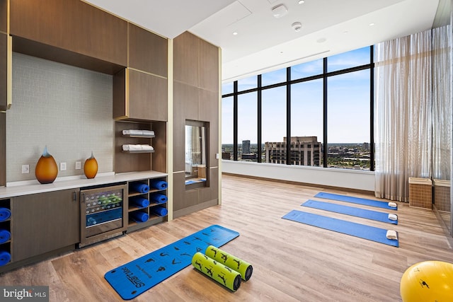 game room featuring beverage cooler, light hardwood / wood-style floors, and expansive windows