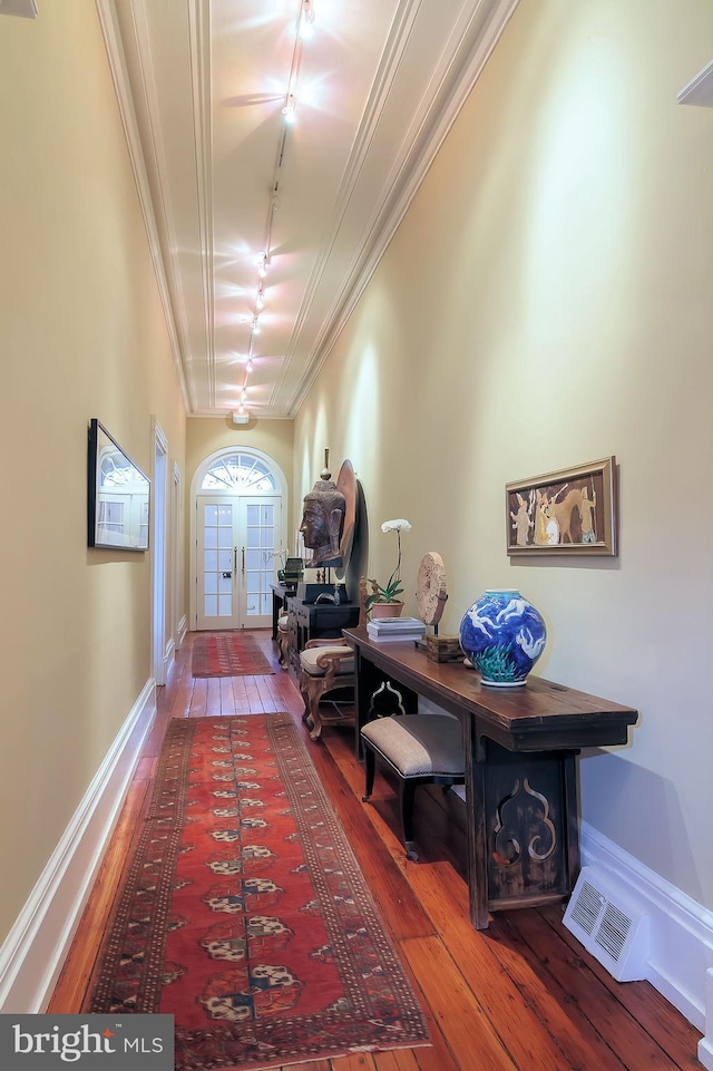 hallway with crown molding, hardwood / wood-style flooring, rail lighting, and french doors