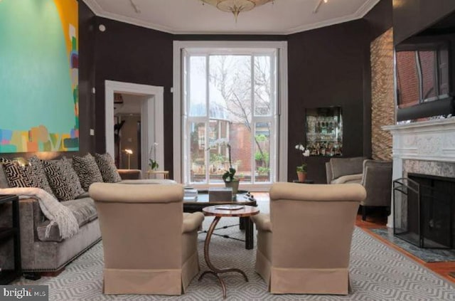 living room featuring a premium fireplace, ornamental molding, and a healthy amount of sunlight