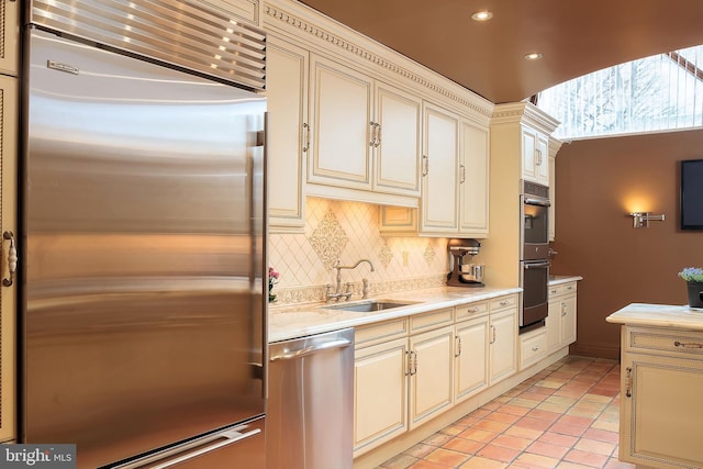 kitchen featuring stainless steel appliances, sink, light tile patterned floors, and cream cabinetry