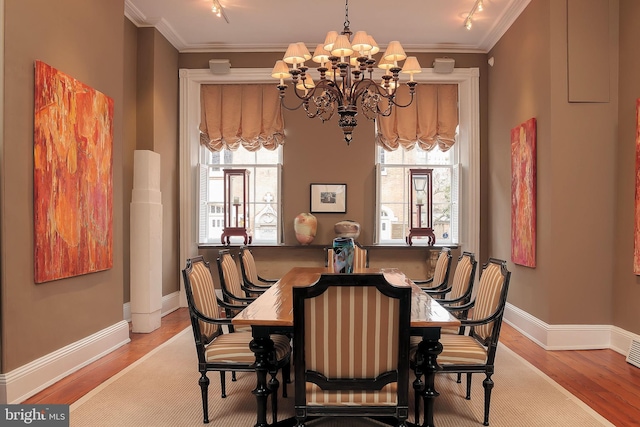 dining space with crown molding, an inviting chandelier, and light wood-type flooring