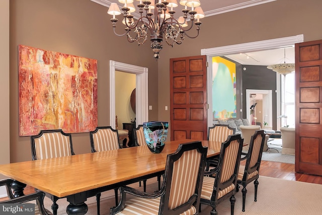 dining area with crown molding, a chandelier, and light wood-type flooring