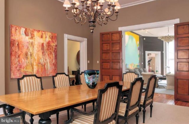 dining room with wood-type flooring, a notable chandelier, and crown molding