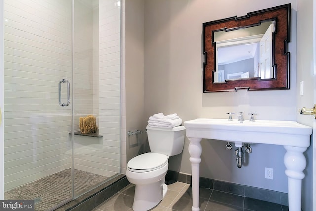 bathroom with a shower with door, tile patterned floors, and toilet