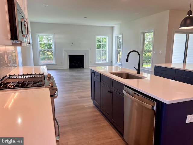 kitchen featuring stainless steel appliances, plenty of natural light, a kitchen island with sink, and sink