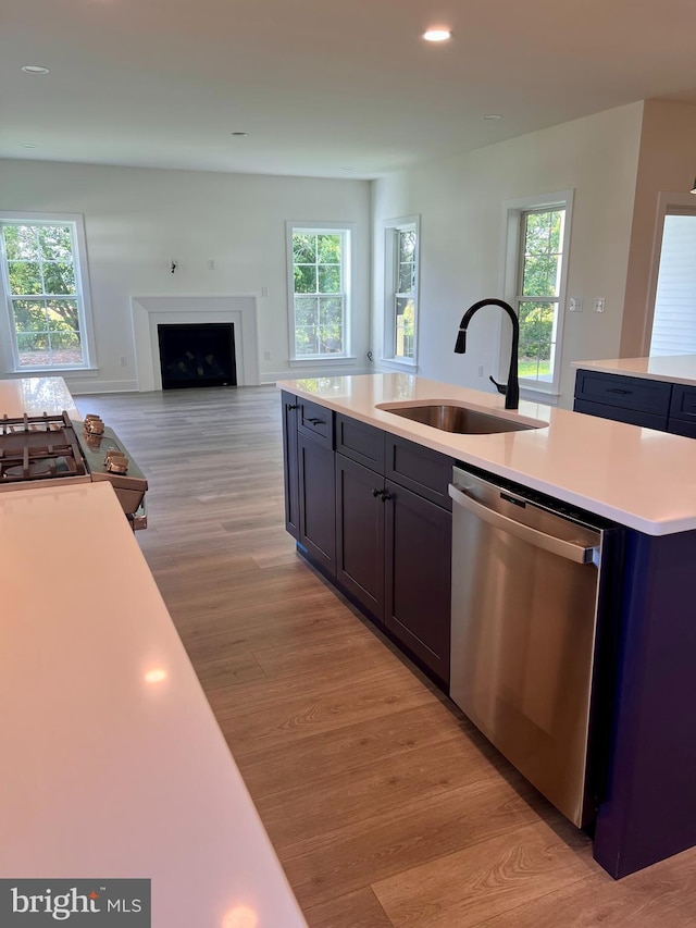 kitchen featuring light hardwood / wood-style floors, dishwasher, sink, and an island with sink