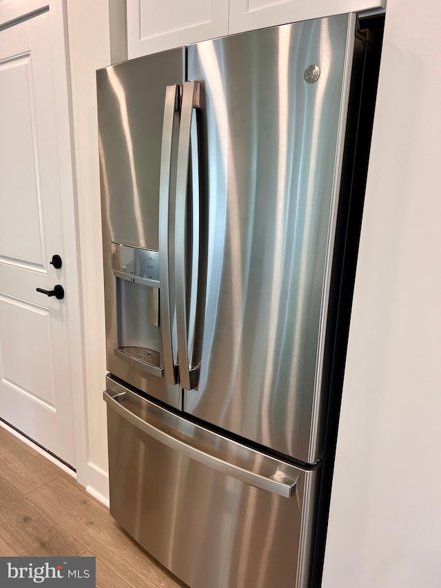 interior details featuring light hardwood / wood-style floors, white cabinetry, and stainless steel fridge with ice dispenser