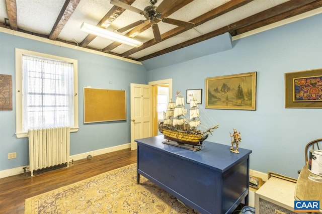 office area featuring radiator heating unit, ceiling fan, dark hardwood / wood-style floors, and beam ceiling