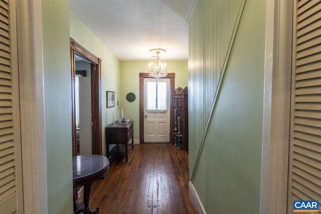 entryway with an inviting chandelier and dark wood-type flooring