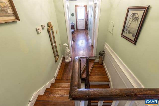 staircase with a notable chandelier and dark wood-type flooring