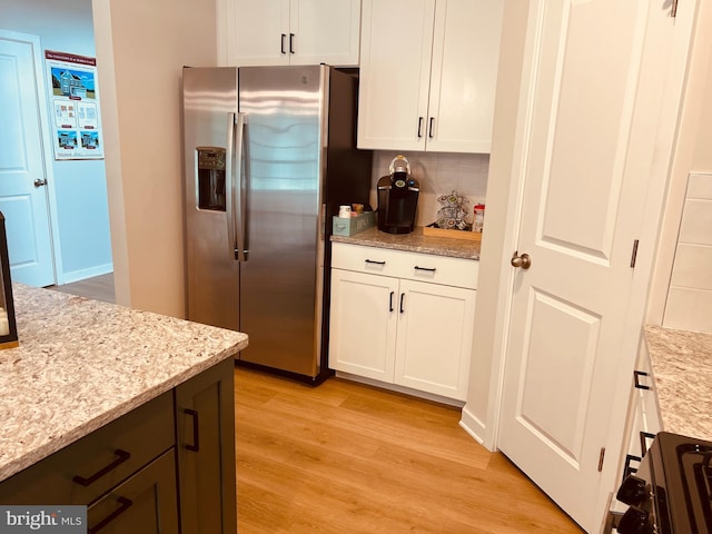 kitchen with white cabinets, stainless steel fridge with ice dispenser, backsplash, and light hardwood / wood-style flooring