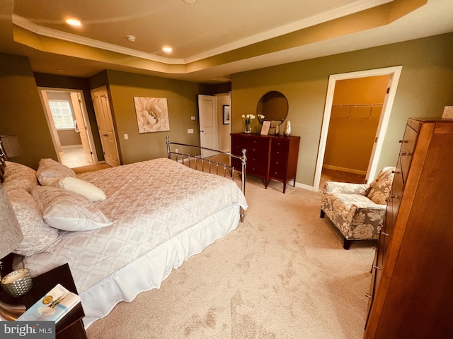 bedroom with a closet, a raised ceiling, light colored carpet, a walk in closet, and ornamental molding