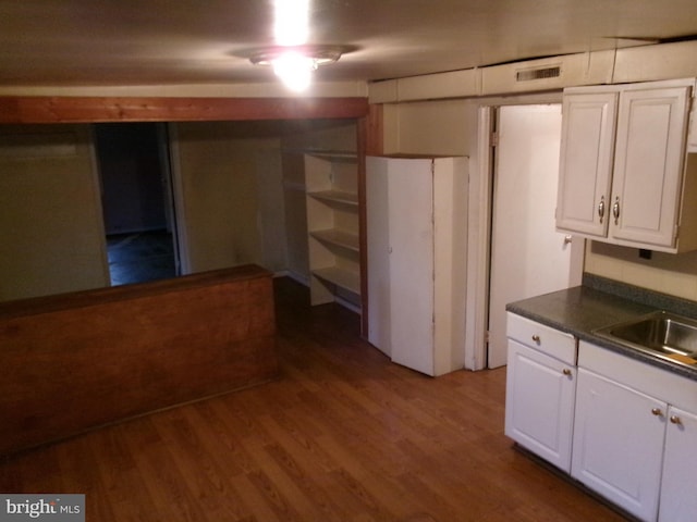 interior space with hardwood / wood-style floors, white cabinetry, and sink