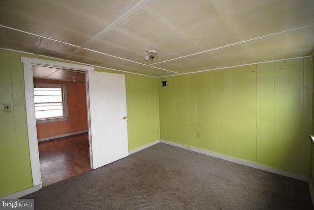 empty room with dark colored carpet and vaulted ceiling