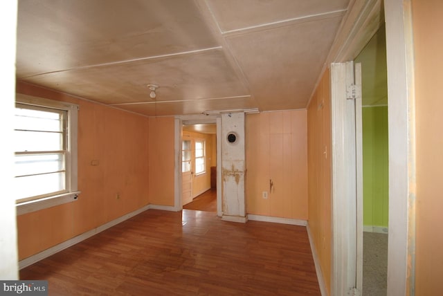 spare room featuring light hardwood / wood-style flooring, wooden walls, and a wealth of natural light