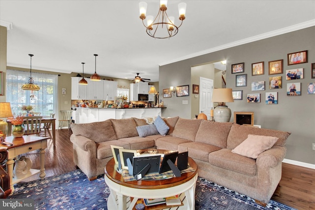 living room with crown molding, dark hardwood / wood-style flooring, and ceiling fan with notable chandelier