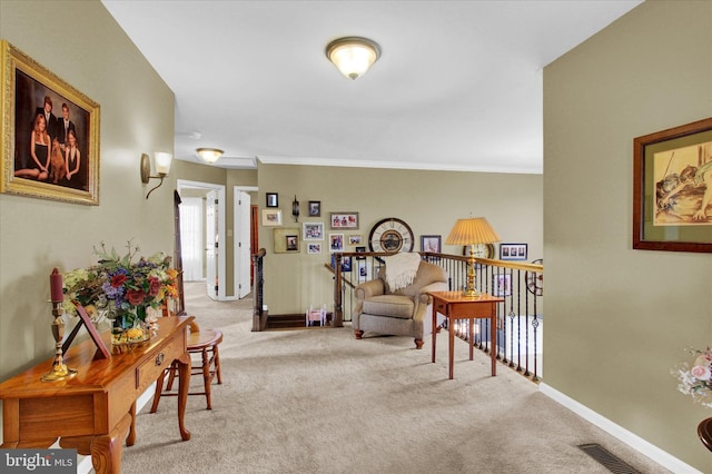 sitting room with ornamental molding and light carpet