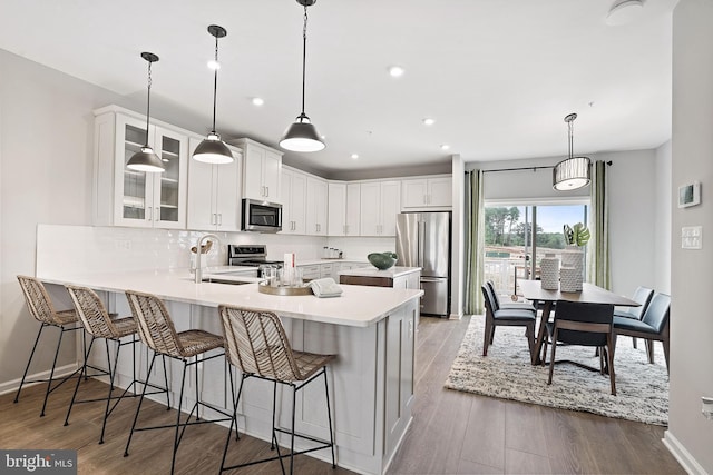 kitchen with white cabinets, light hardwood / wood-style flooring, appliances with stainless steel finishes, and pendant lighting