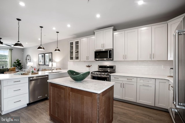 kitchen featuring appliances with stainless steel finishes, pendant lighting, backsplash, dark hardwood / wood-style flooring, and white cabinetry