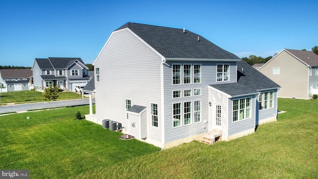 rear view of house featuring central air condition unit, entry steps, a lawn, and roof with shingles