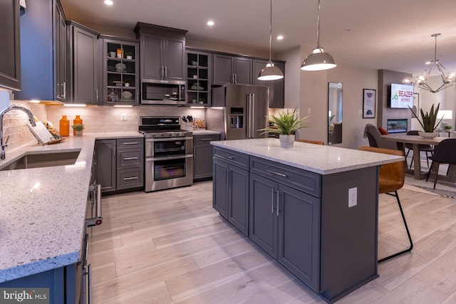 kitchen with sink, light hardwood / wood-style floors, stainless steel appliances, decorative light fixtures, and a notable chandelier