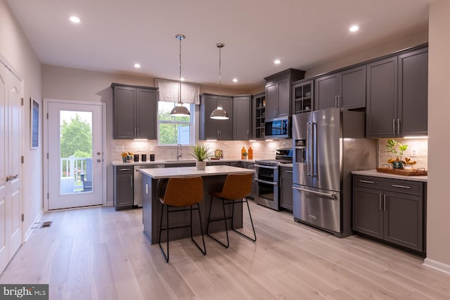 kitchen with a kitchen island, hanging light fixtures, a healthy amount of sunlight, appliances with stainless steel finishes, and a kitchen bar