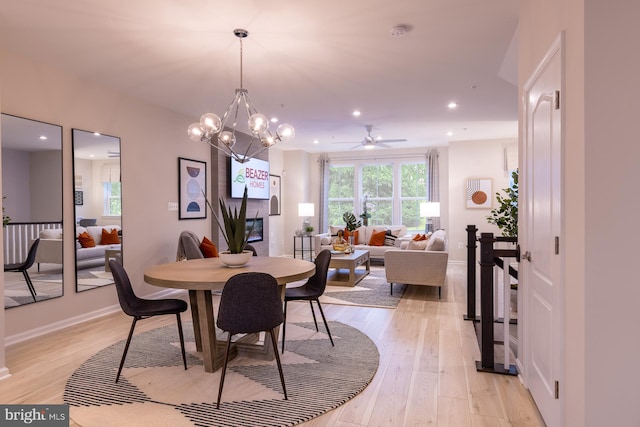 dining space with light hardwood / wood-style flooring and ceiling fan with notable chandelier